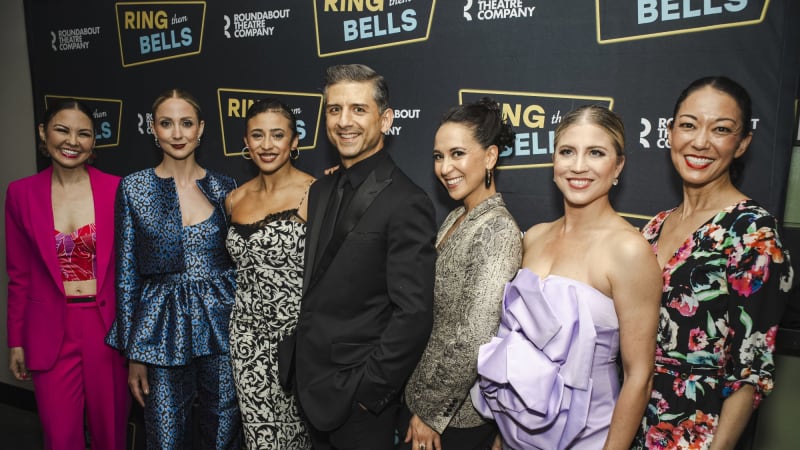 A group of people in formal attire pose on the red carpet.
